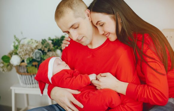 Cute family have fun in decorating room. Beautiful mother with little children and husband. Family in a red sweaters